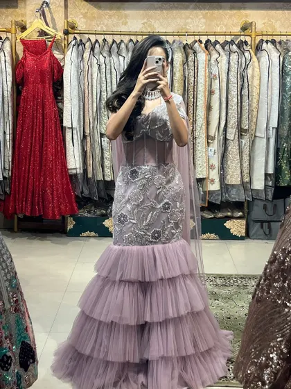 A mirror selfie showing off the full look of our lavender mermaid gown. The tiered ruffles and cape-style dupatta create a modern and elegant silhouette.
