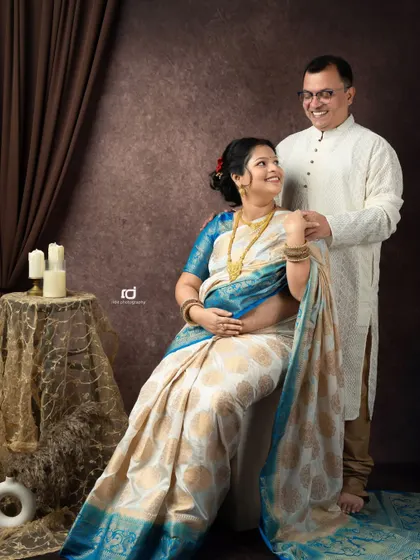 A joyful and classic portrait of an expecting couple in ethnic wear. The smiles they share show the happiness and excitement for the new arrival.