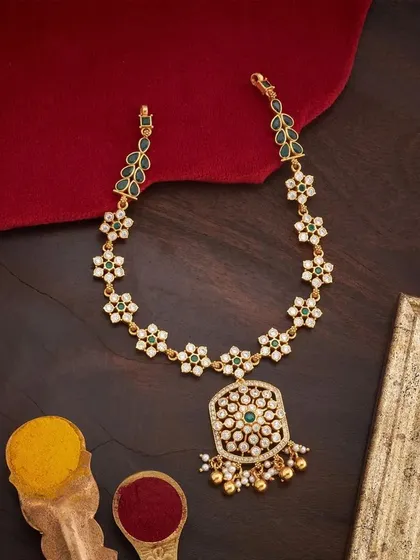 A delicate floral necklace set with white and green stones. The design features a chain of star-shaped flowers leading to a larger, ornate pendant with pearl drops, perfect for adding a touch of freshness to your look.