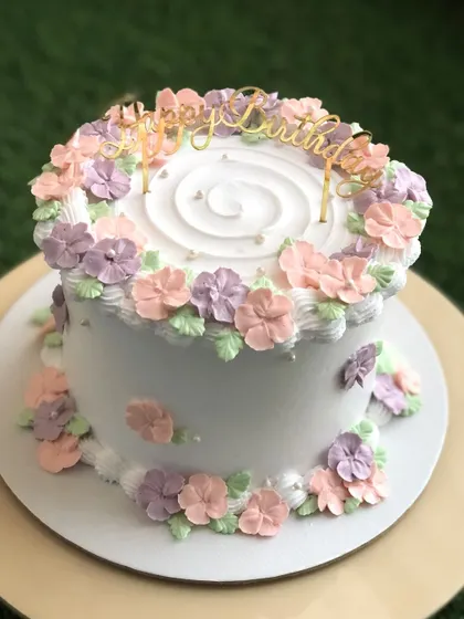 A pretty pastel floral cake with pink, purple, and peach flowers.