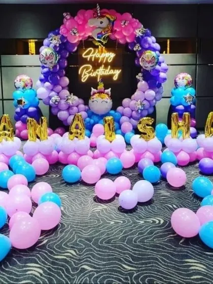A magical unicorn-themed birthday party. This setup features a circular balloon arch in pink, purple, and blue, with unicorn and name details, perfect for a fun celebration.