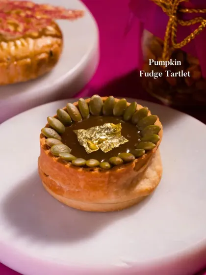 A stunning Pumpkin Fudge Tartlet, decorated with pumpkin seeds and a touch of edible gold leaf for a luxurious finish.