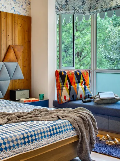 The kids' bedroom is a vibrant space designed for playful comfort. A custom bay window nook with colorful upholstery serves as a daybed with built-in storage, offering the perfect perch for daydreaming while looking out at the Himalayan view.