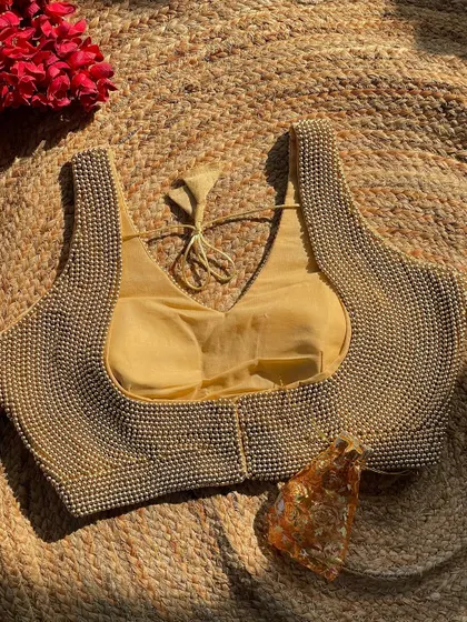 The same handcrafted pearl blouse, shown here in a classic golden hue. This piece is designed to be easily paired with a variety of sarees for weddings and festive events.