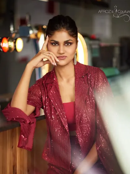 A close-up portrait of a model wearing the red sequined jacket. The shot highlights the sparkle of the fabric and the sharp cut of the lapels.