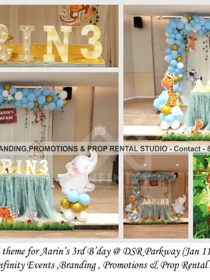 A simple safari theme for a 3rd birthday at DSR Parkway. The decor includes a curtain backdrop with a blue and gold balloon garland, cute animal cutouts, and a light-up name and number display.