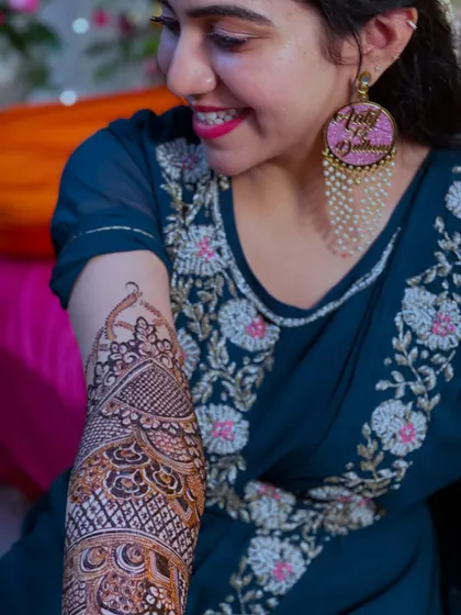 A close-up of the bride's smile and her detailed arm henna. She's also wearing beautiful "Ladkiwale" earrings.