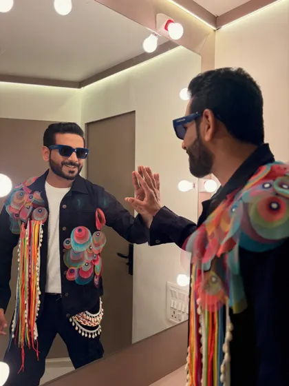 Getting ready for a show in a custom denim jacket with vibrant, artistic embellishments. The mirror check is part of the pre-show ritual.