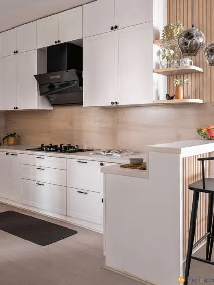 Another angle of the white kitchen, showing the breakfast bar with black stools and open shelving for decor. The design is perfect for small spaces, making the kitchen feel open and airy.