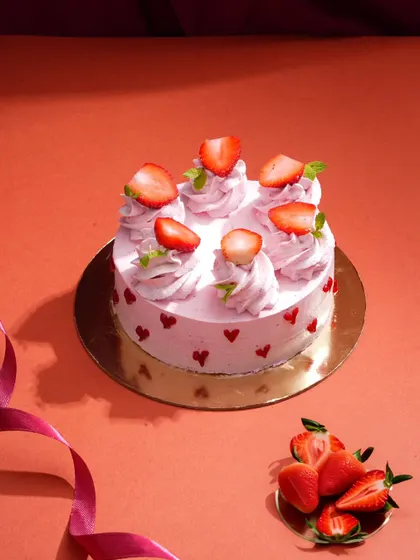This charming strawberry cake is styled with a simple, colorful background and a flowing ribbon to create a celebratory feel. It’s a sweet and simple setup perfect for showcasing specialty cakes.