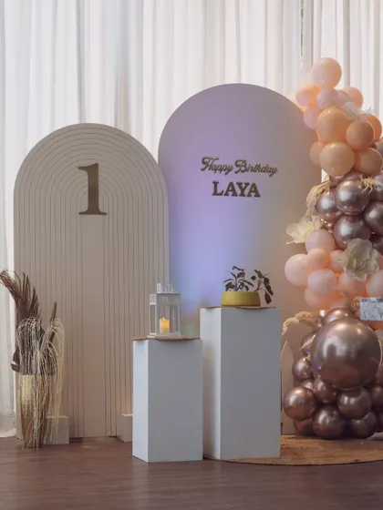 Another view of the minimalist birthday setup, showing the beautiful interplay of the arched backdrops, balloon garland, and the intimate dining table.