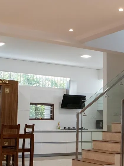 An open-concept layout in the 'Isha-Vaasyam' home, where the dining area, kitchen, and staircase are all visually connected to create a bright and social space.
