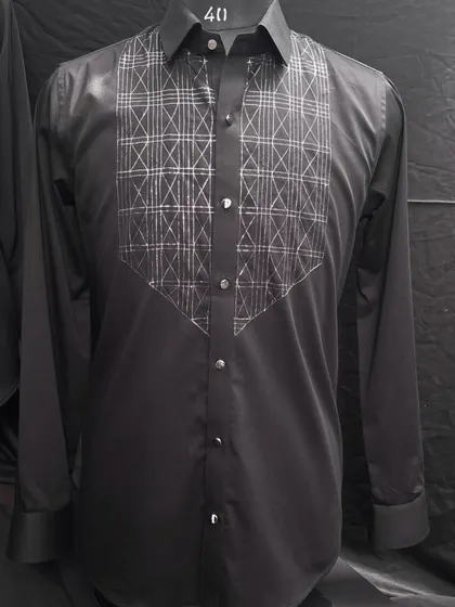 This black shirt features a bib of geometric, intersecting lines embroidered in silver thread. It's a modern, architectural take on shirt embellishment, designed for a sharp, contemporary look.