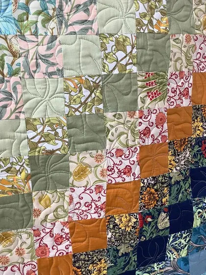 A close-up of the color-wash wall piece, showing the variety of floral prints and the simple quilting.