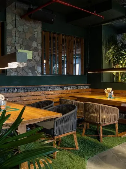 Another perspective of the seating at Social Offline, this shot emphasizes the comfortable and rustic feel of the wooden benches and woven chairs.
