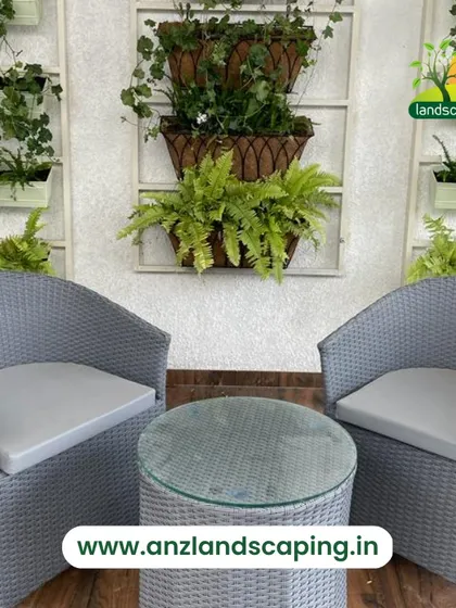 A simple and elegant balcony seating area, with wicker chairs and a table set against a wall decorated with hanging and wall-mounted planters.
