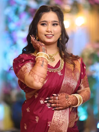 A happy bride showing off her henna. The makeup is kept soft and glowing to complement the rich color of her saree and the intricate mehndi design.