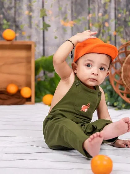 A playful moment during a sitter session. The little one is adjusting his cap, showing off his budding personality for the camera.