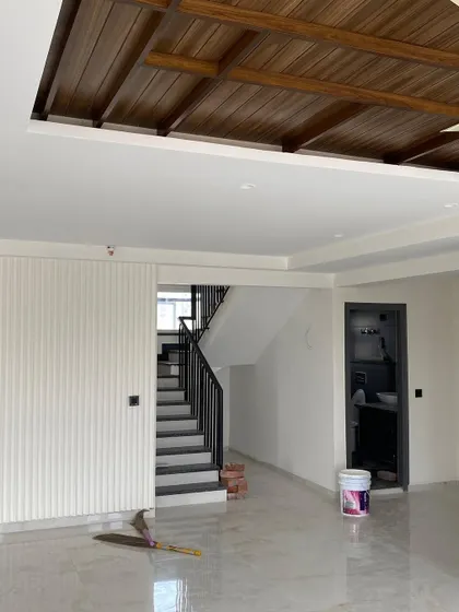 The penthouse living area taking shape, with a wooden false ceiling and fluted wall panels creating a warm and modern foundation.
