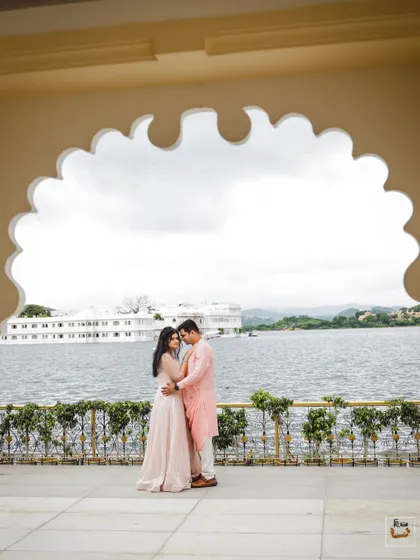 A beautiful post-wedding portrait in Udaipur, with the iconic Lake Palace in the background, framed by a traditional arch.