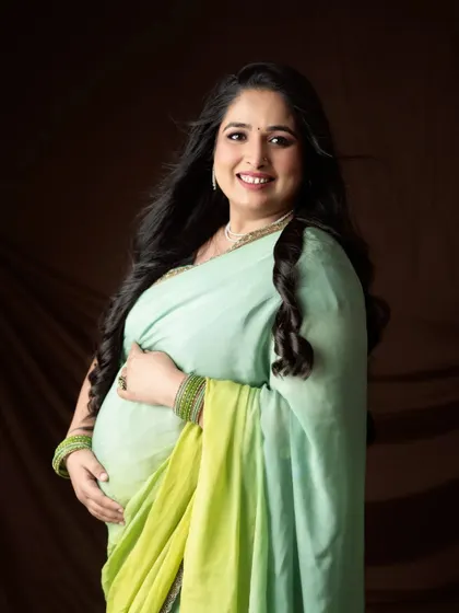 A radiant solo portrait. The mom-to-be's hair is blowing gently, adding a touch of movement and life to this beautiful shot in a green saree.