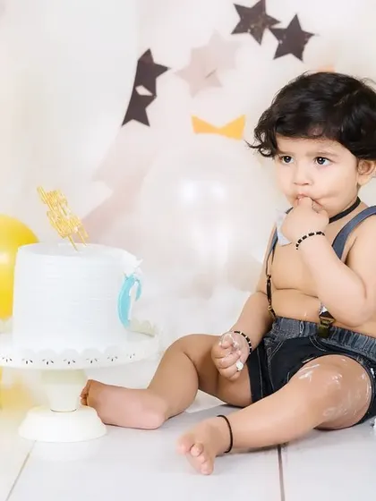 A thoughtful moment during a cake smash, as the baby boy curiously tastes the frosting from his finger.