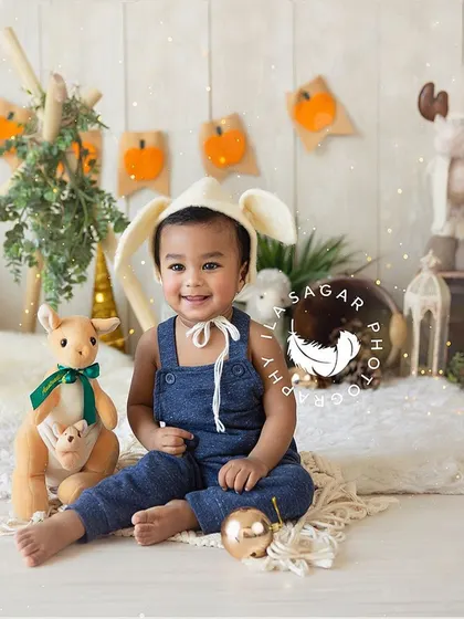 A happy little boy in a bunny hat. This milestone session captures his cheerful personality in a fun, woodland-themed setup.