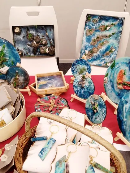 A selection of my resin art and handmade jewelry displayed at a pop-up. The vibrant blues and natural textures attract a lot of attention and appreciation.