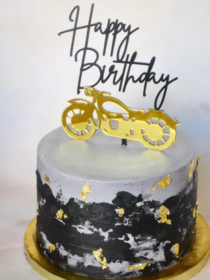 One for the bike lovers. A sleek cake with a black and grey textured finish, topped with a custom gold motorcycle accent.