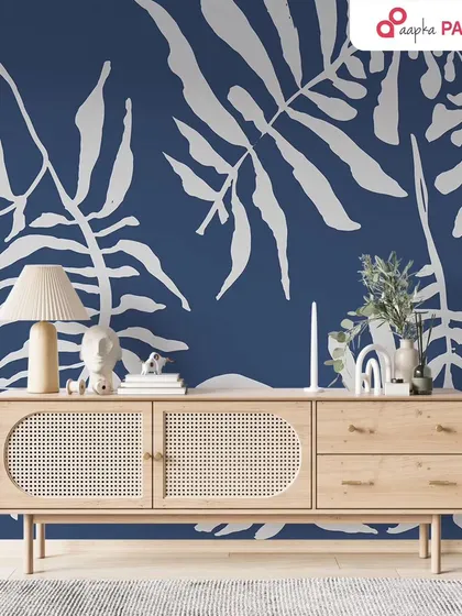 A bold living room accent wall featuring large, white tropical leaf patterns on a deep blue background. This design makes a dramatic and stylish statement.