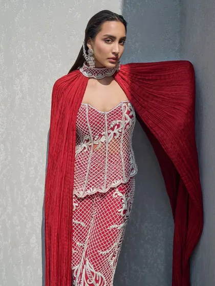 A fully pearl-embellished corset paired with tailored pants and a sweeping crushed cape that doubles as a dramatic choker. This is elegance with an edge.