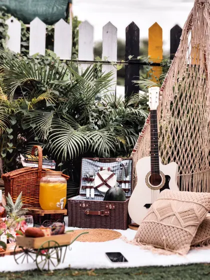 Let's turn your backyard into a bohemian dream. This picnic setup features a macrame teepee, plush cushions, and a guitar for a relaxed, musical vibe, perfect for a casual get-together or celebration.