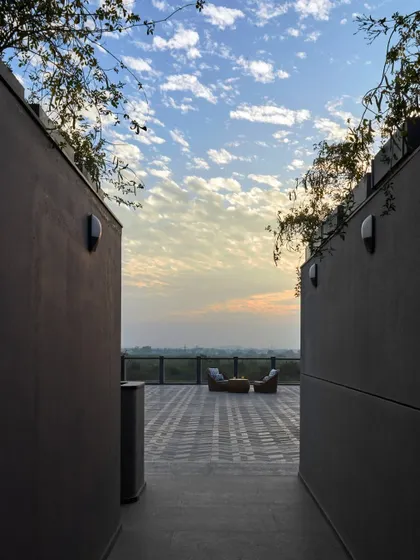 A view from the Baid Residence terrace at dusk, showing a quiet seating area perfect for enjoying the sunset over the forest. We design these outdoor spaces as extensions of the home's living areas.