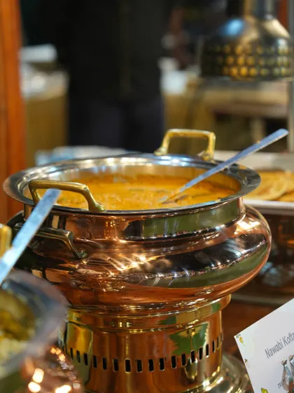 A traditional copper chafing dish holding our rich and creamy Nawabi Kofta curry, a royal dish fit for a grand celebration.