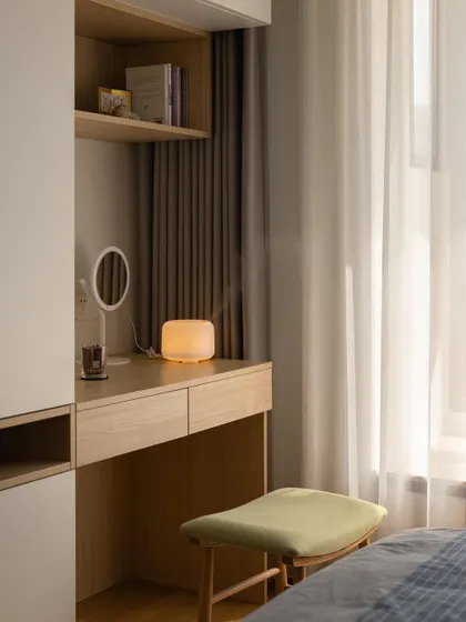 A minimalist bedroom design featuring a built-in wooden desk and wardrobe unit. The clean lines and natural wood finish create a calm and clutter-free environment, perfect for a study or guest room.