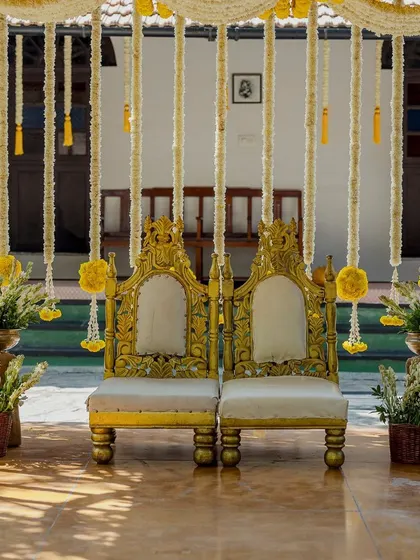 The seating for the couple at the Haldi, with ornate golden chairs.