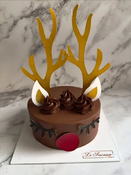A cute and festive Reindeer Cake for Christmas, made with rich chocolate cake and decorated with golden antlers and a red nose.