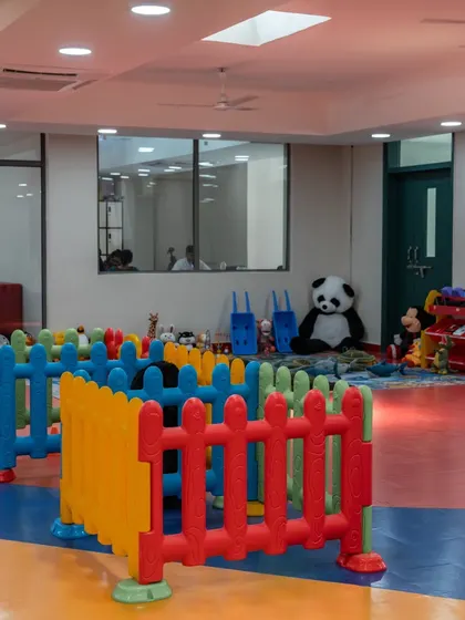 A safe and engaging play area designed for toddlers. The space is enclosed with colorful fencing and filled with soft toys and age-appropriate equipment, allowing for free play under supervision.
