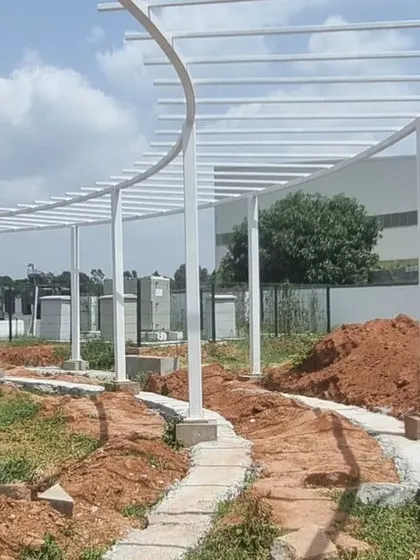 The curved metal framework for a long pergola being erected at Aamby City, Hoskote. This structure will eventually be covered in climbing plants, creating a green, shaded walkway for residents.