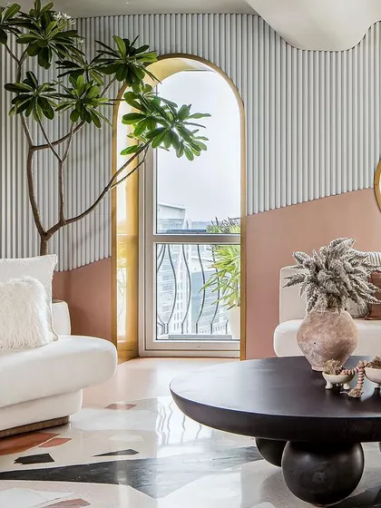 The living room is the heart of the home, with arched windows and a circular mirror reflecting the greenery outside.