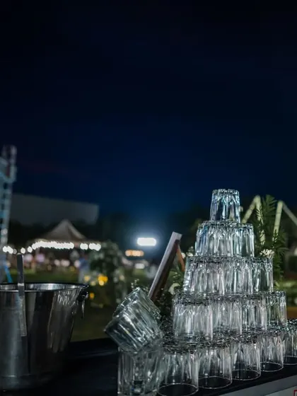 A wide shot of a glass tower on our bar, set against the backdrop of an outdoor event at dusk.