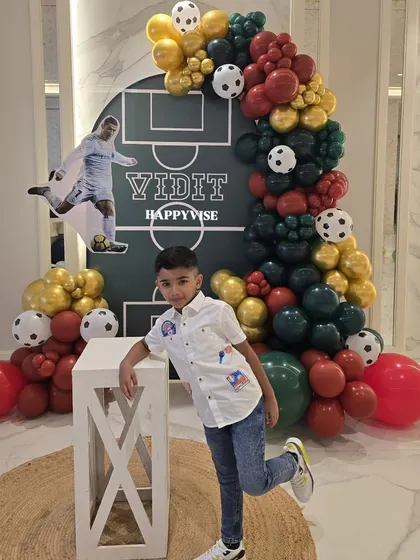 The birthday boy, Vidit, posing with his awesome football-themed party decor. It's always a joy to see the kids enjoying the world I've created for them.
