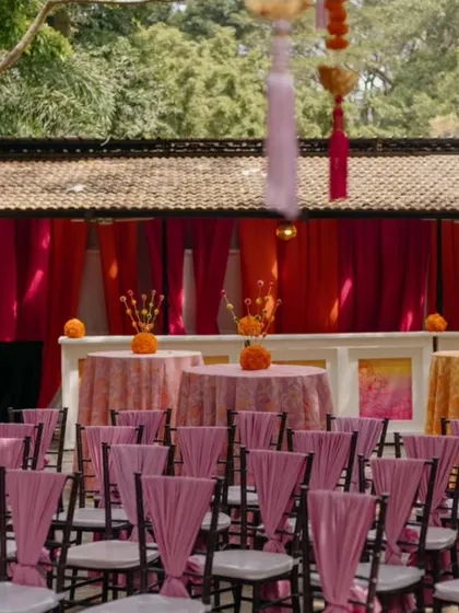 Guest seating for a marigold-themed Haldi, with pink chair ties adding a pop of contrasting color to the vibrant orange and yellow decor.