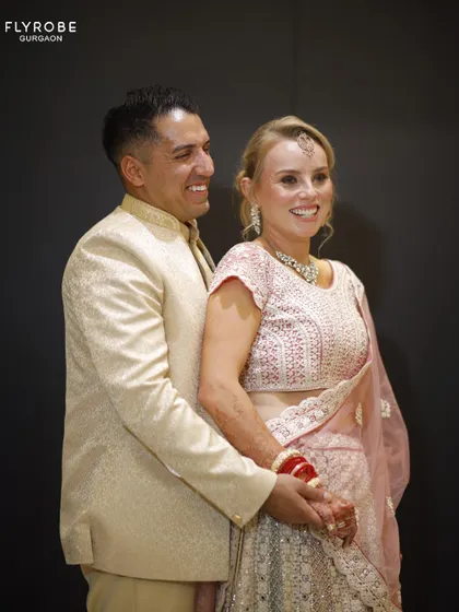 This international couple looks absolutely radiant. Her pastel pink lehenga and his cream sherwani are a beautiful combination for a day wedding.