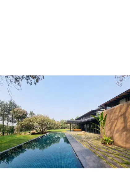 The long infinity pool at the Lakeshore house reflects the sky and the surrounding trees. The home is a low slung filter for the elements, built from metal and earth from the very site.