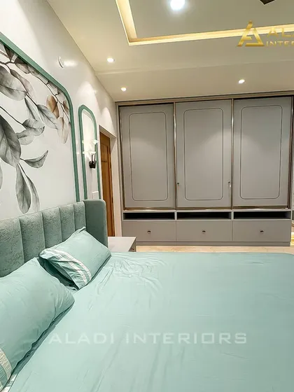 This view highlights the custom grey wardrobe with integrated drawers and the matching dressing table, demonstrating a complete and cohesive bedroom furniture solution.
