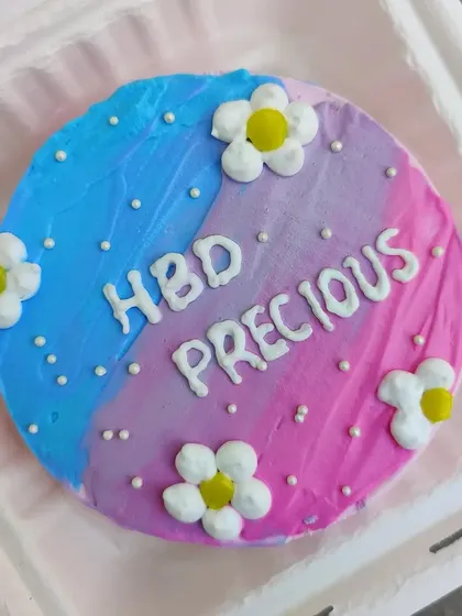 A pretty bento cake with a split pink and blue design, decorated with little fondant daisies.