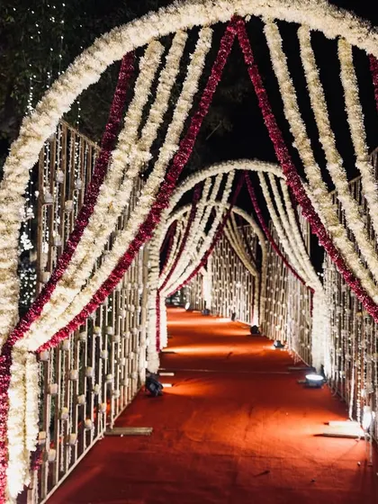 An alternate view of a grand entrance walkway, this time adorned with beautiful garlands of white and red flowers for a classic and romantic feel.