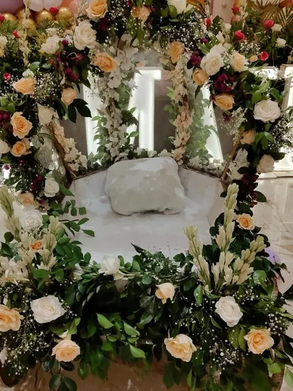 A close-up of the baby entry cart, exquisitely decorated with fresh white and peach roses and other foliage.