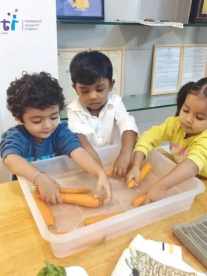 Children carefully wash carrots in a tub of water. This activity is part of our Exercises of Practical Life, which are designed to build independence and coordination.